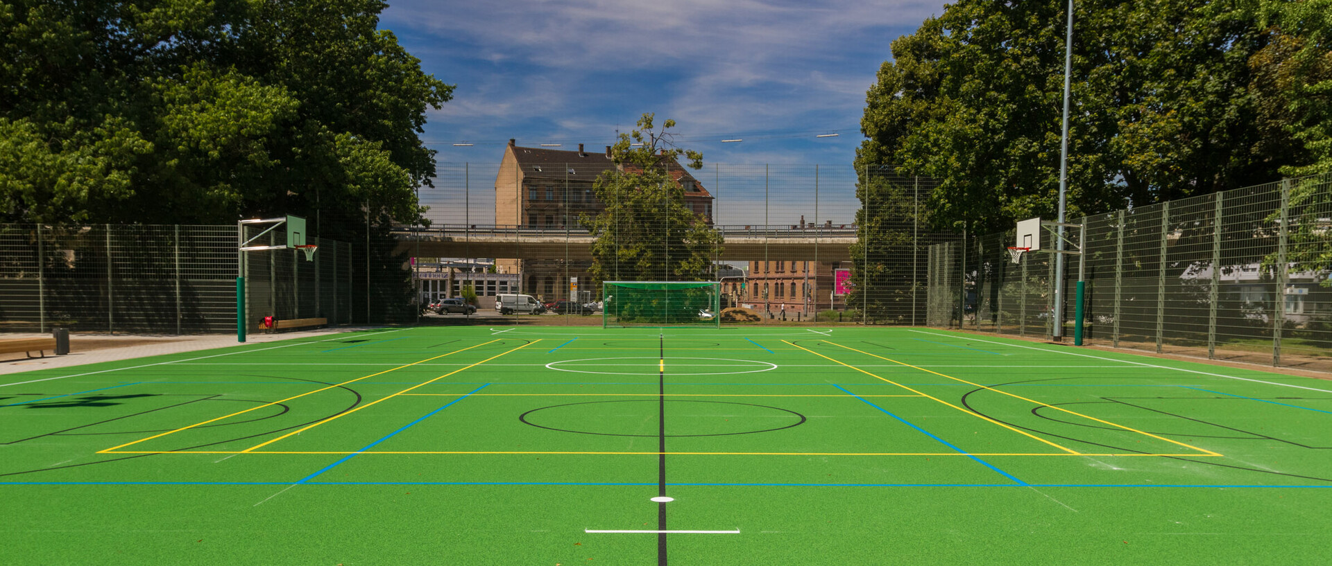 Alfred-Delp-Sportanlage im Friedrichspark. Grüner Hartboden mit Basketball- und Fußball-Toren