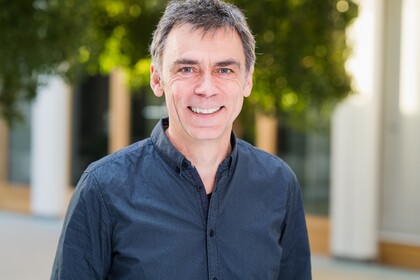 Frank Kalter hat kurze graue Haare und lacht in die Kamera. Er trägt ein blaues Hemd.