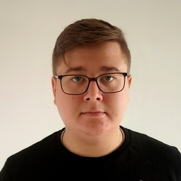 Portrait of Leon Siefken. He is wearing a black shirt and standing in front of a white wall.
