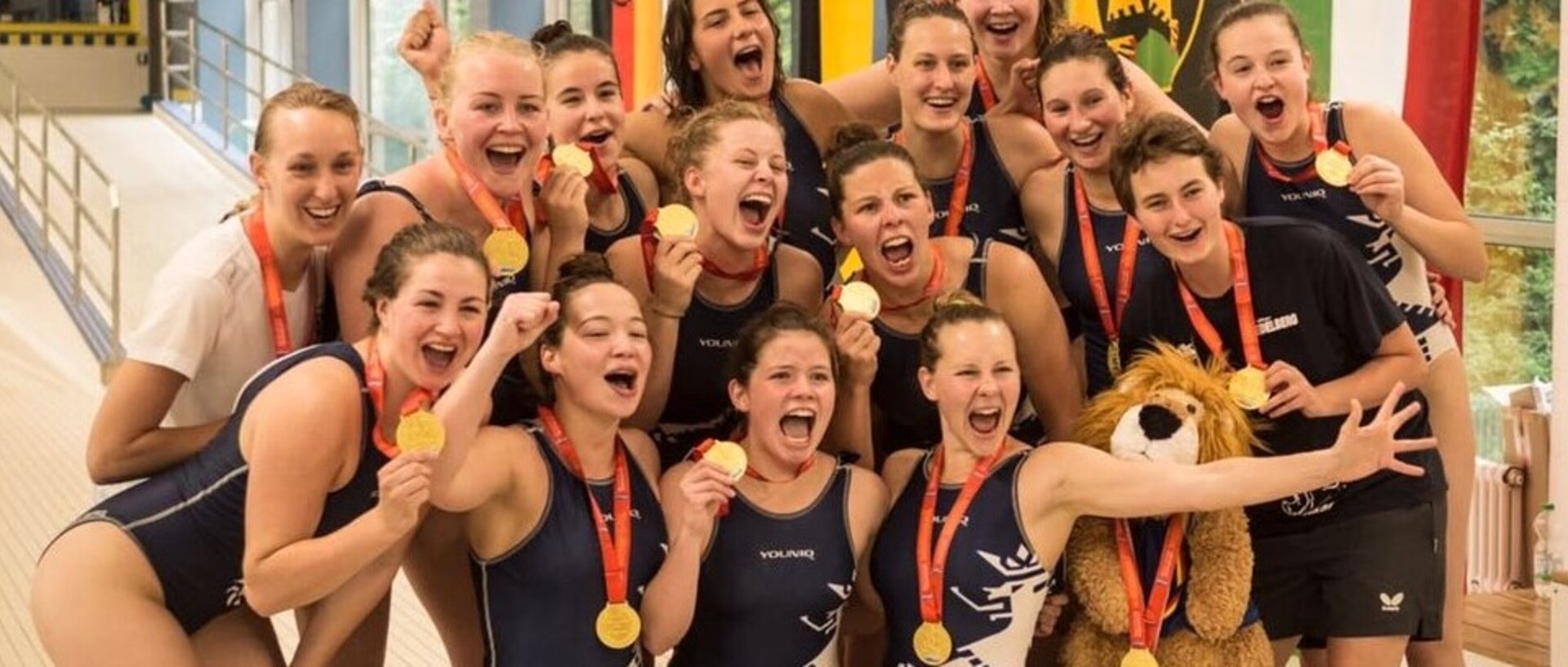 Eine Gruppe von Schwimmerinnen lachend mit ihren Medaillen in der Schwimmhalle