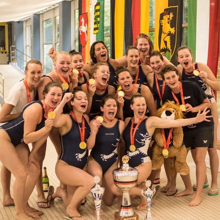 Eine Gruppe von Schwimmerinnen lachend mit ihren Medaillen in der Schwimmhalle