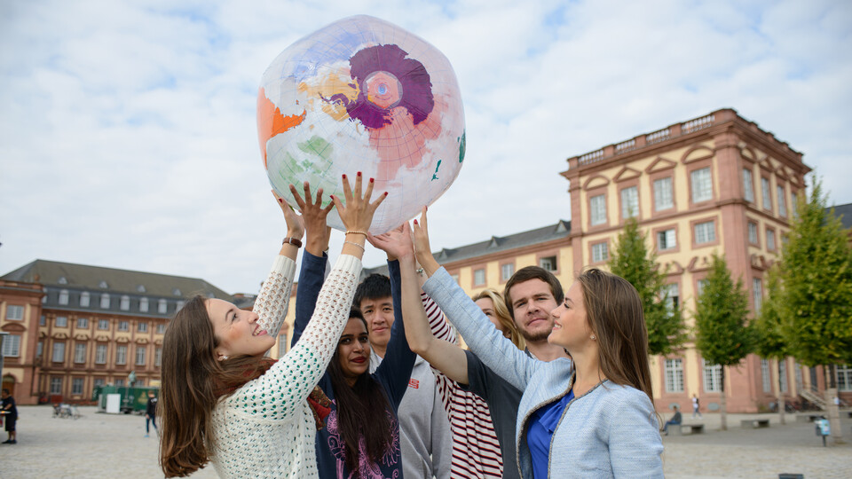 Studierende mit aufblasbarem Globus auf dem Ehrenhof. 