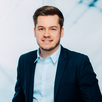Patrick Dillenberger hat kurze braune Haare. Er trägt ein hellblaues Hemd und ein dunkles Jackett.