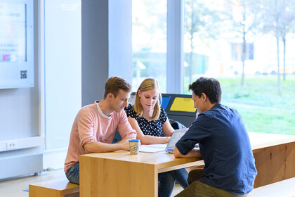 Drei Studierende sitzen an einem Tisch und lernen