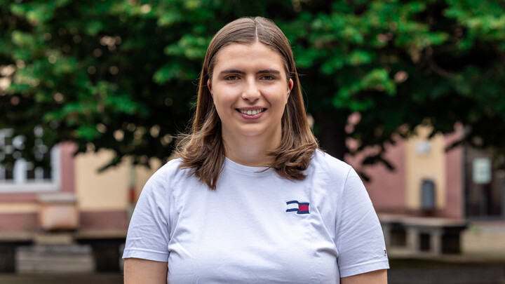 Porträtfoto von Leonie Sindel, die auf dem Campus der Uni Mannheim steht.