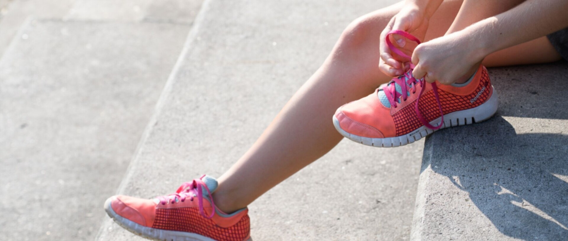 Runner sits on stairs and ties her running shoes