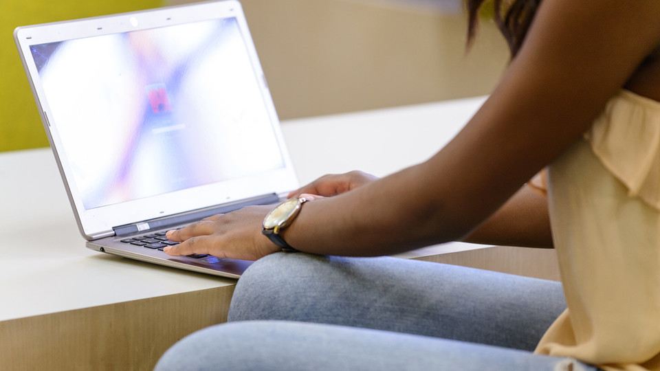 Eine Studentin meldet sich an ihrem Laptop an.