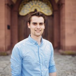 Ein Porträt von Bastian Biemer. Er trägt kurzes braunes Haar und ein hellblaues Hemd.