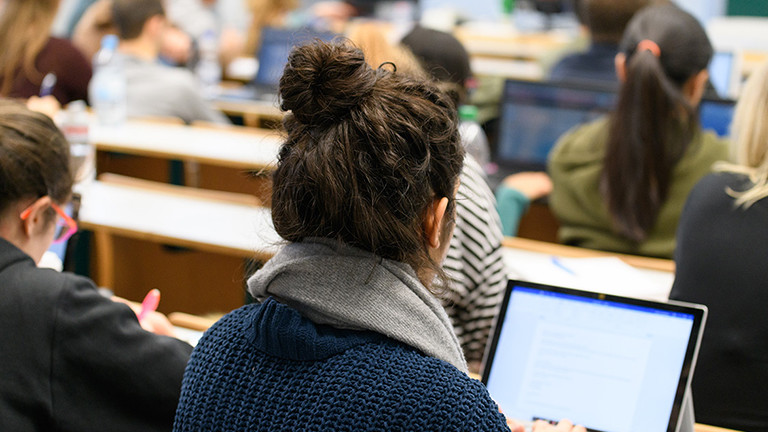 Mehrere Studierende sitzen in einem Hörsaal.