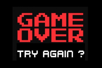 Der rot-weiße aus Computerspielen bekannte Schriftzug "Game Over - Try again?" leuchtet auf schwarzem Hintergrund.
