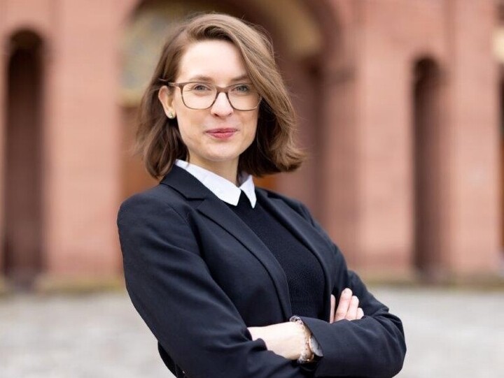 Svenja Behrendt hat die Arme verschränkt und blickt in die Kamera. Sie steht auf dem Ehrenhof des Mannheimer Schlosses.