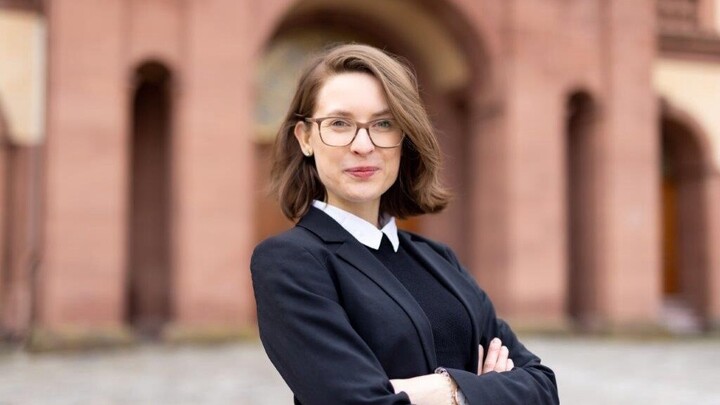 Svenja Behrendt hat die Arme verschränkt und blickt in die Kamera. Sie steht auf dem Ehrenhof des Mannheimer Schlosses.