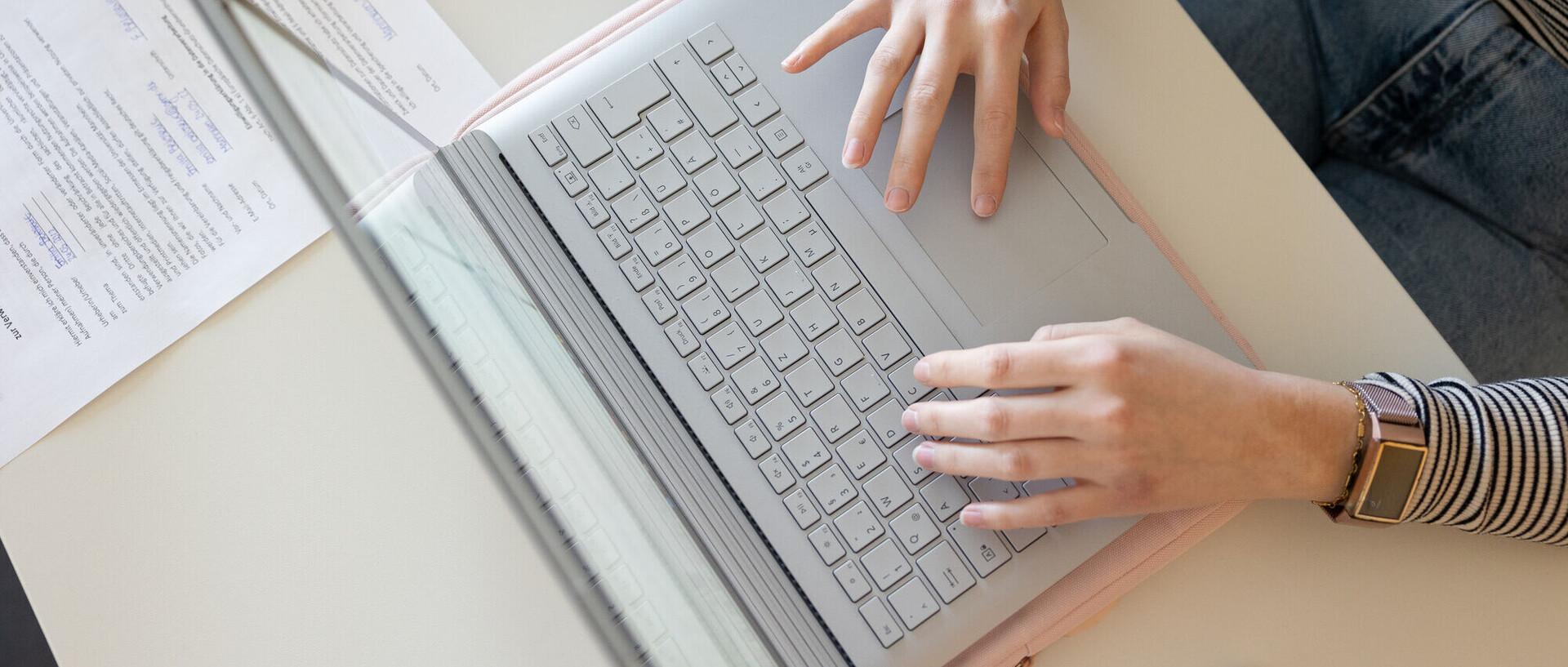 Eine Studentin arbeitet an einem Laptop. Die Aufnahme ist von oben, zu sehen sind das Gerät und die die Hände.