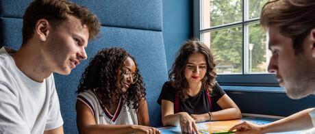 Studierende sitzen an einem Tisch im Learning Center und tauschen sich aus.