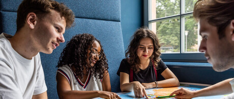 Studierende sitzen an einem Tisch im Learning Center und tauschen sich aus.