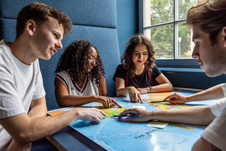 Studierende sitzen an einem Tisch im Learning Center und tauschen sich aus.