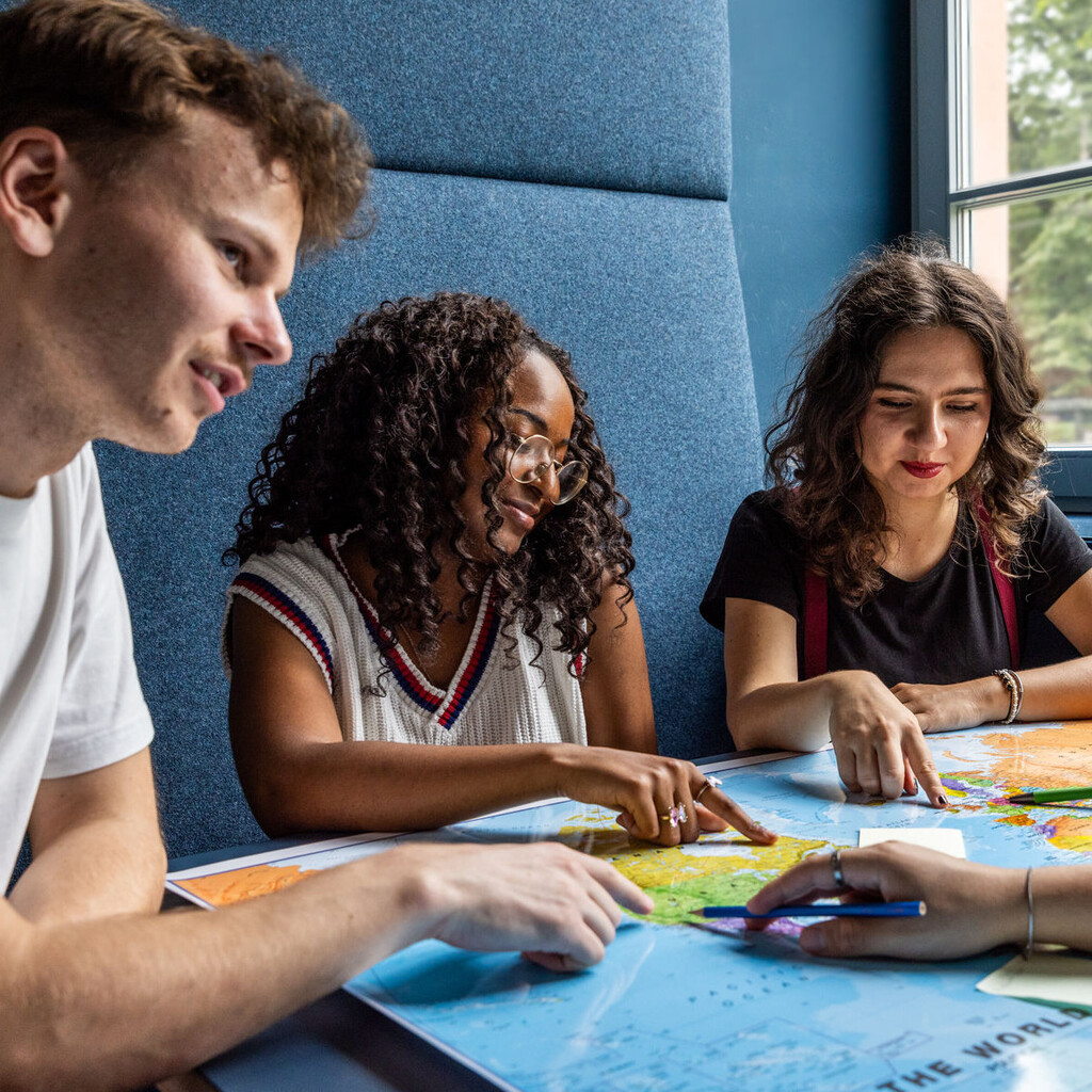 Studierende sitzen an einem Tisch im Learning Center und tauschen sich aus.