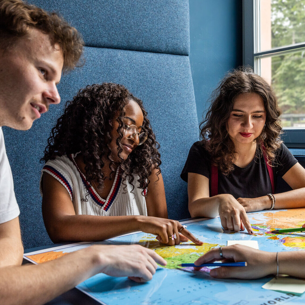 Studierende sitzen an einem Tisch im Learning Center und tauschen sich aus.