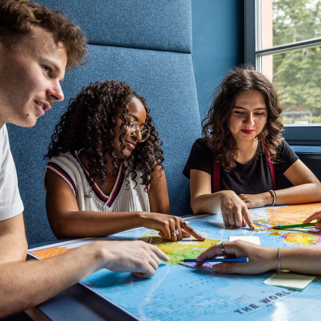 Studierende sitzen an einem Tisch im Learning Center und tauschen sich aus.