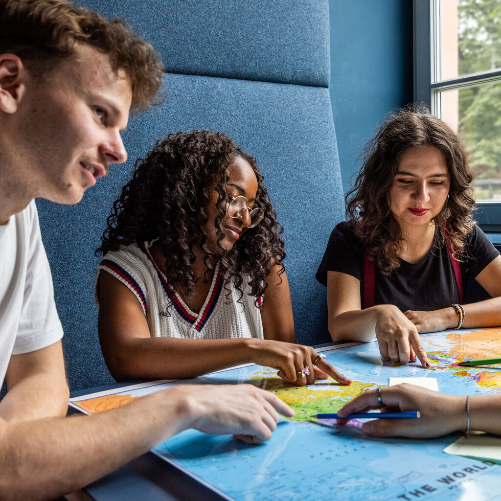 Studierende sitzen an einem Tisch im Learning Center und tauschen sich aus.