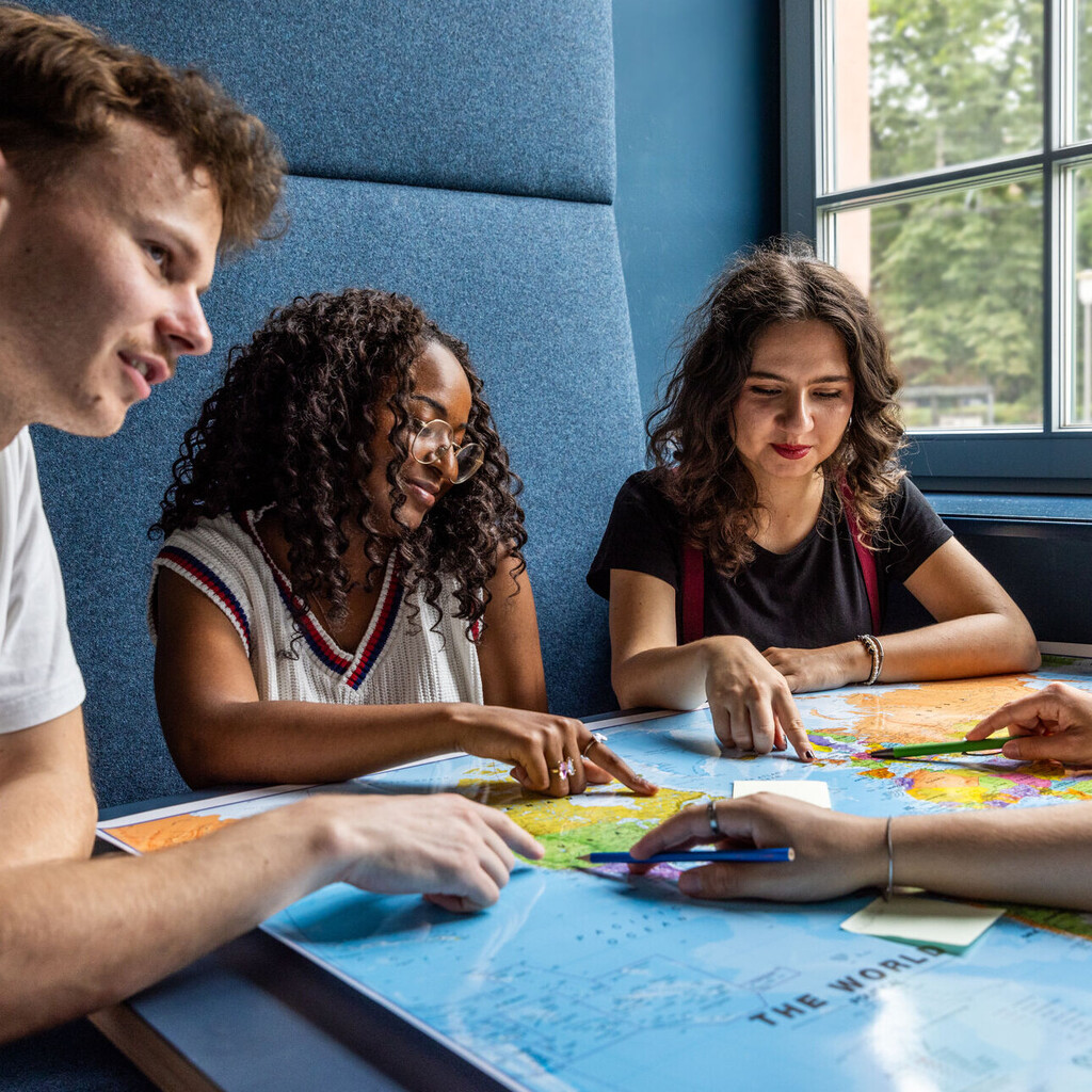 Studierende sitzen an einem Tisch im Learning Center und tauschen sich aus.