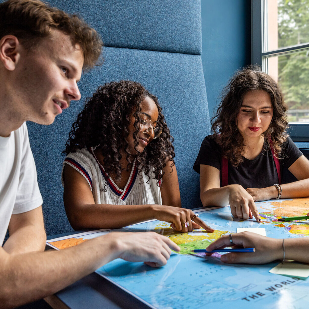 Studierende sitzen an einem Tisch im Learning Center und tauschen sich aus.