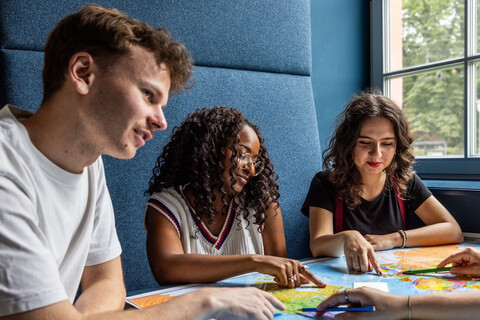Studierende sitzen an einem Tisch im Learning Center und tauschen sich aus.