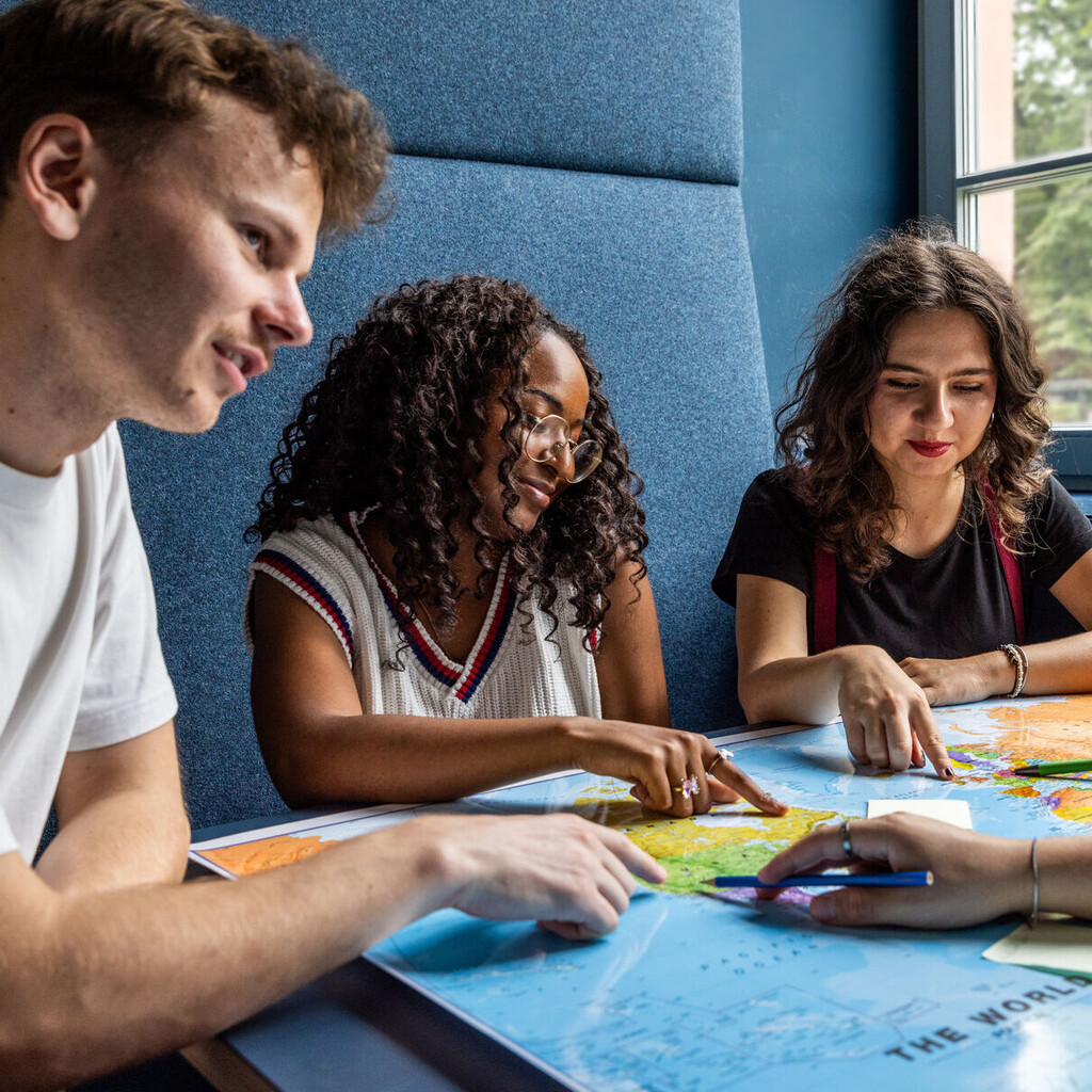 Studierende sitzen an einem Tisch im Learning Center und tauschen sich aus.