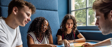 Studierende sitzen an einem Tisch im Learning Center und tauschen sich aus.