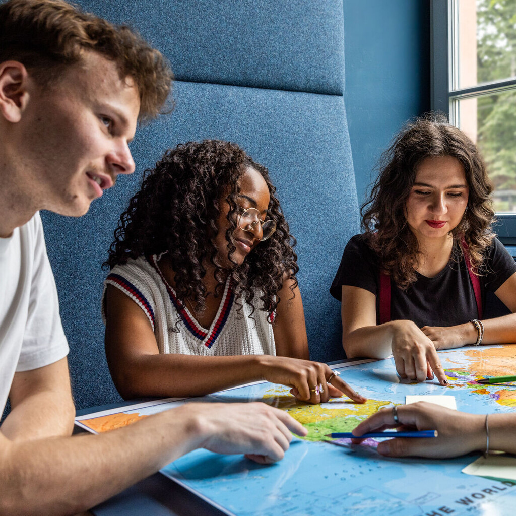 Studierende sitzen an einem Tisch im Learning Center und tauschen sich aus.