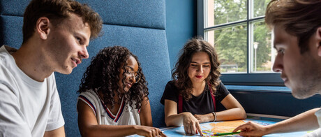 Studierende sitzen an einem Tisch im Learning Center und tauschen sich aus.