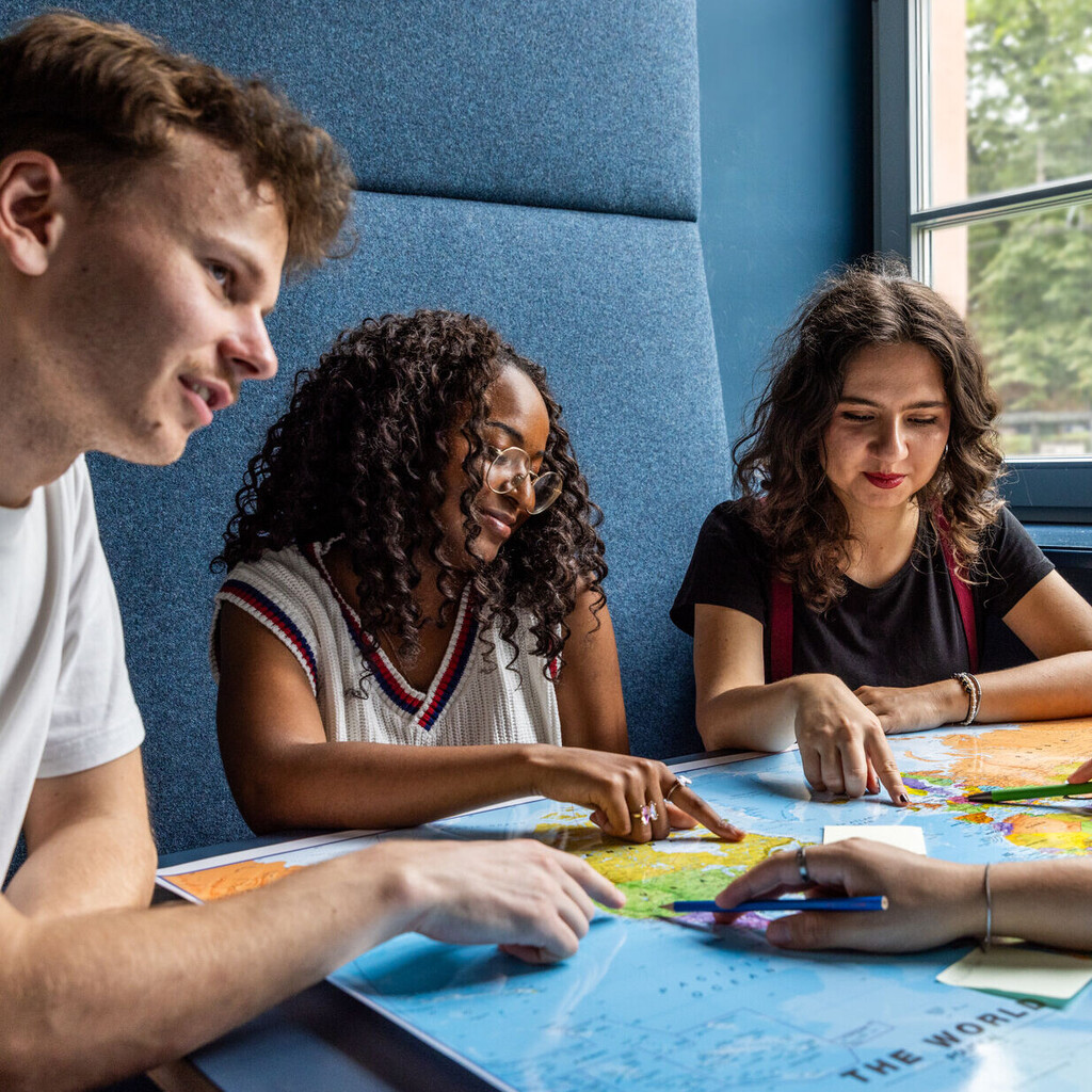 Studierende sitzen an einem Tisch im Learning Center und tauschen sich aus.