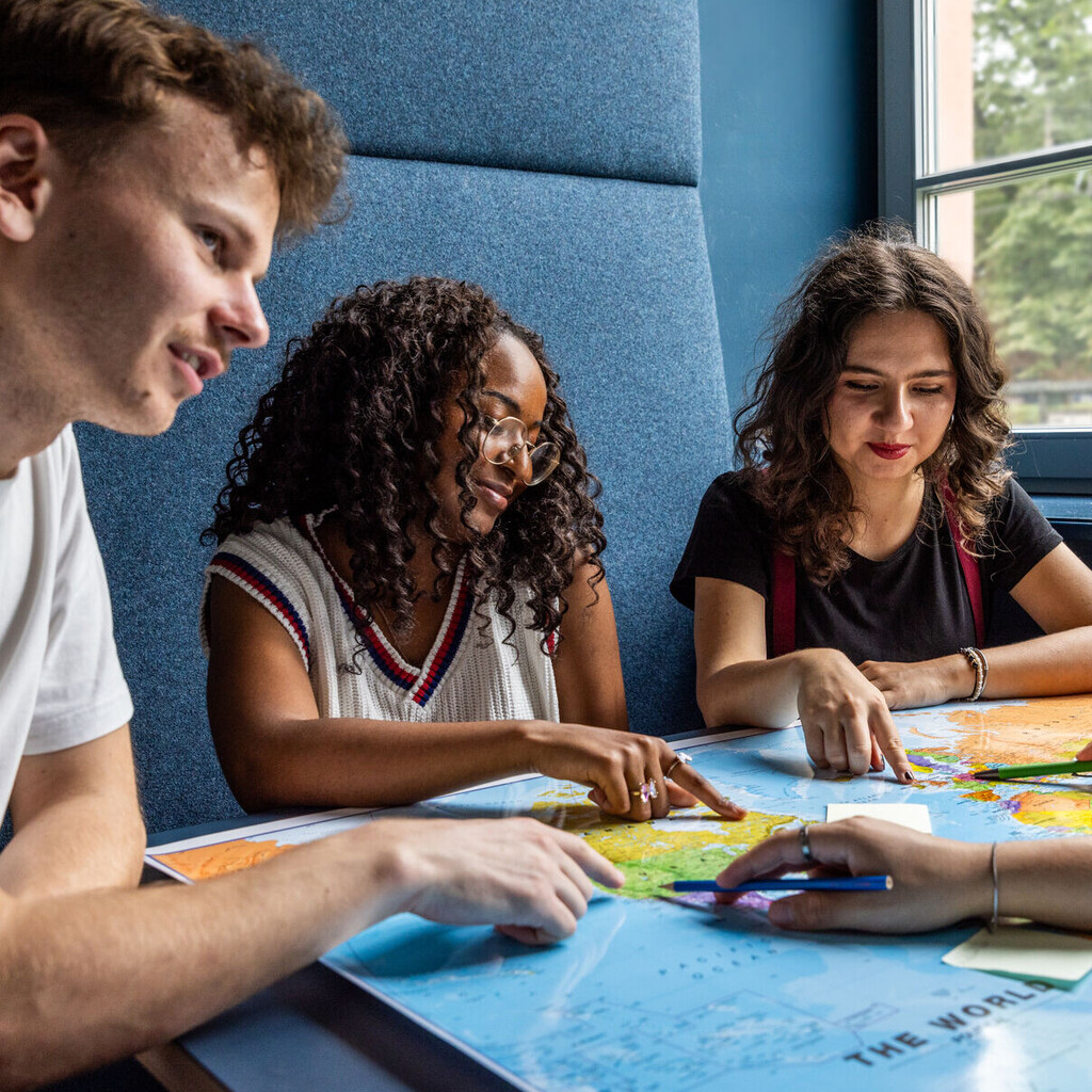 Studierende sitzen an einem Tisch im Learning Center und tauschen sich aus.