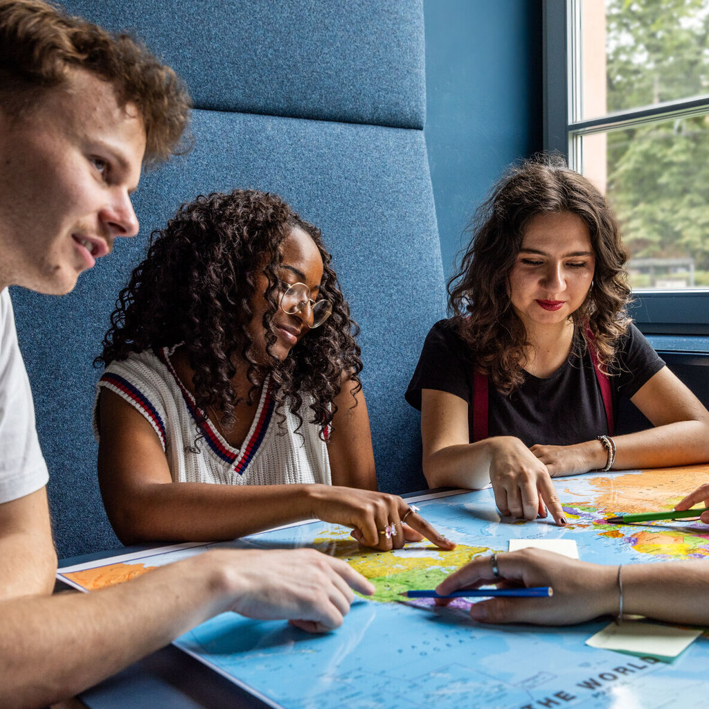 Studierende sitzen an einem Tisch im Learning Center und tauschen sich aus.