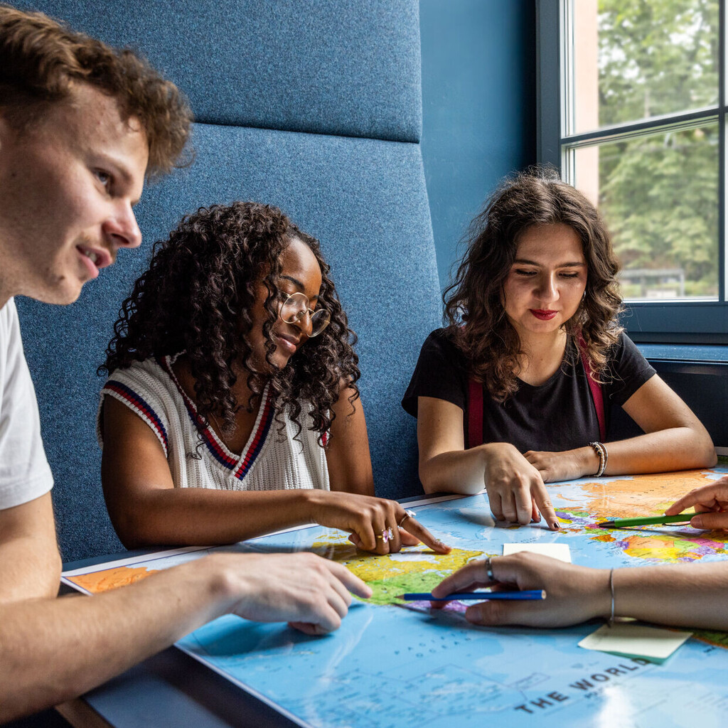 Studierende sitzen an einem Tisch im Learning Center und tauschen sich aus.