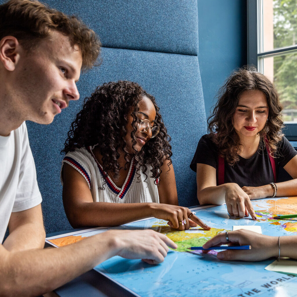 Studierende sitzen an einem Tisch im Learning Center und tauschen sich aus.