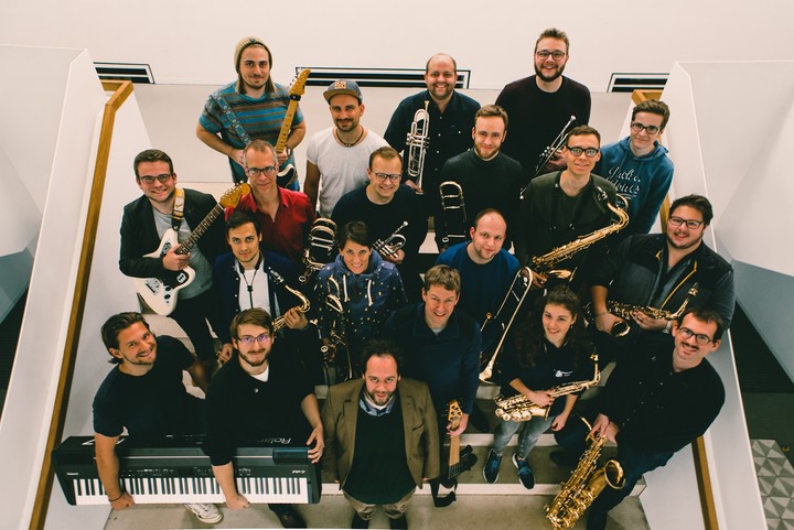 Mitglieder eines Orchesters stehen mit ihren Instrumenten auf einer Treppe.