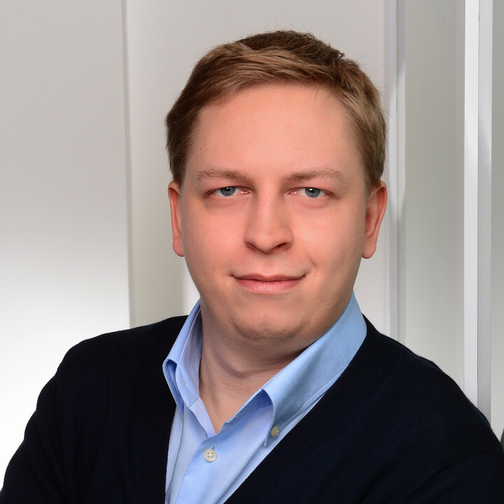 Maximilian Phlipps hat kurze blonde Haare. Er trägt ein hellblaues Hemd und ein schwarzes Jackett.