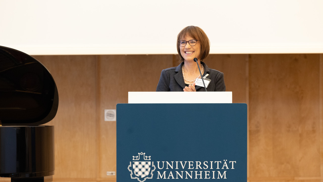 Prof. Dr. Annette Kehnel steht lachend an einem Redner*innenpult