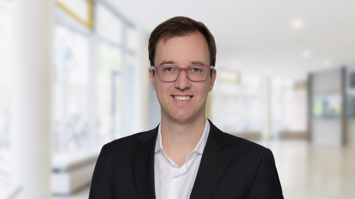 Professor Andreas Gulyas trägt ein weißes Hemd und ein schwarzes Sakko und lächelt in die Kamera.