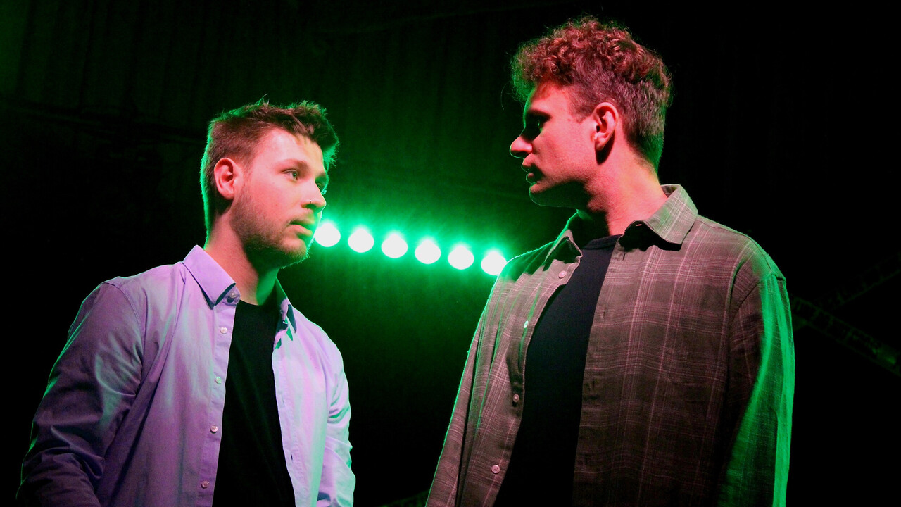 Szenenbild des Unitheaters. Zwei Studierende blicken sich an.