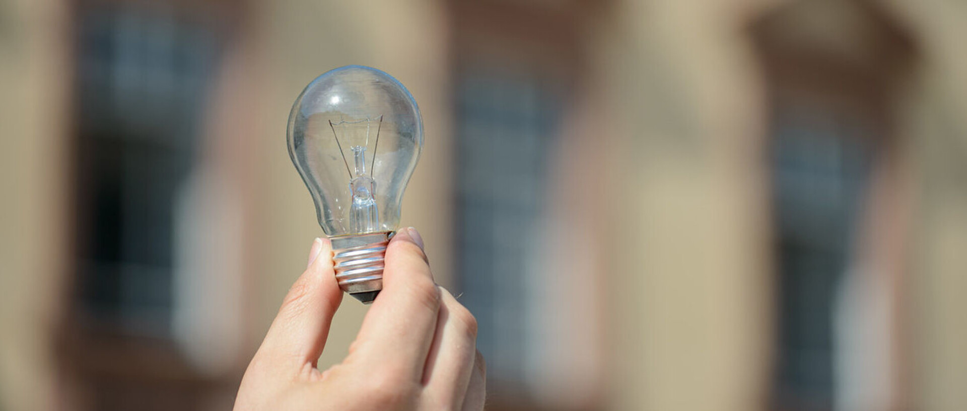 One hand holds up a light bulb.