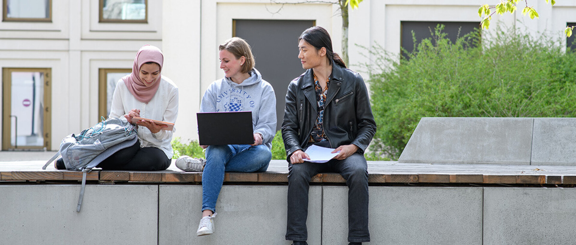 A group of students are sitting in the courtyard of B6, 30-32 and are talking.