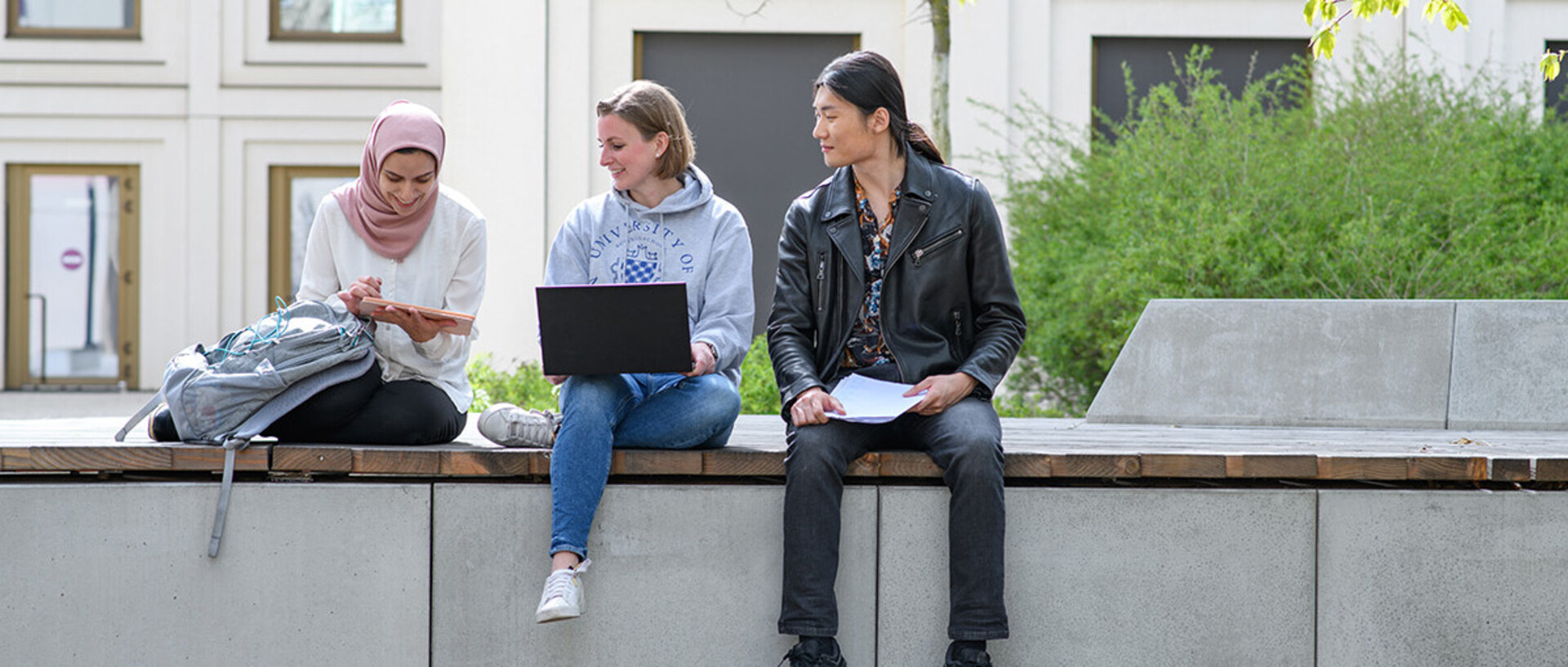 A group of student is talking and sitting on banks in the courtyard of B6, 30-32.