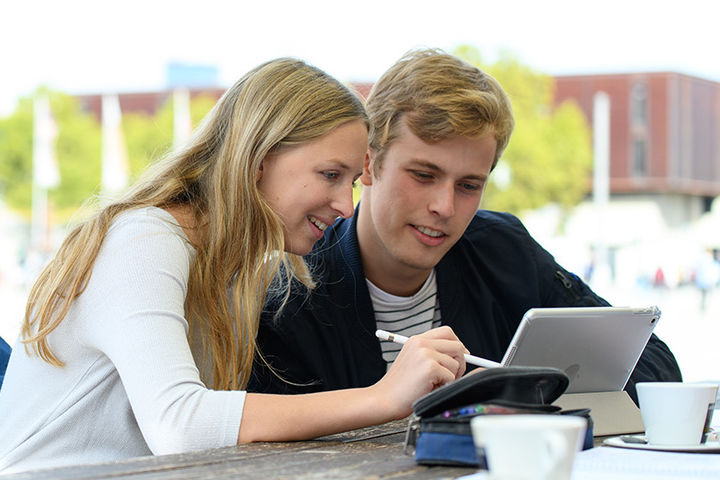 Studierende im Schlosshof im Gespräch mit Tablet