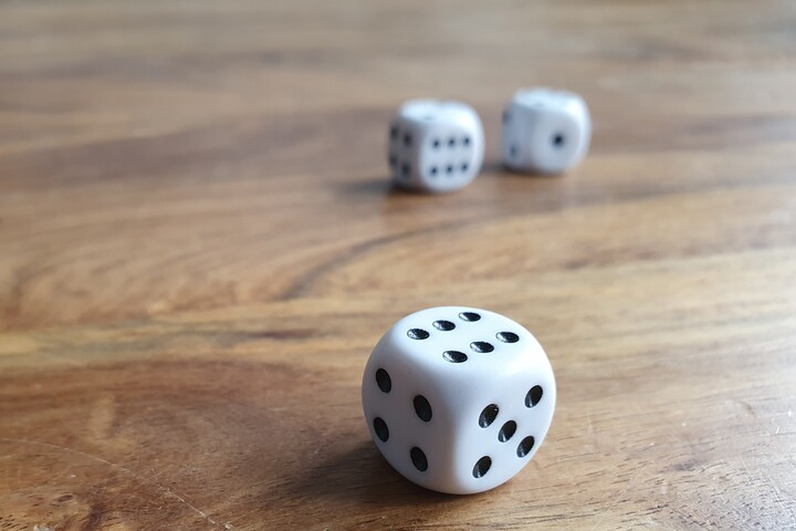 Three dice on a wooden table.
