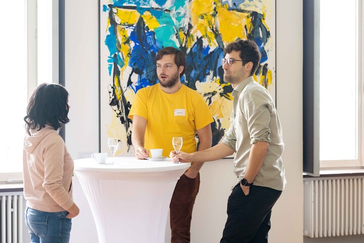 Drei Personen unterhalten sich an einem Stehtisch