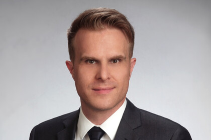 Portraitfoto von Florian Stahl. Er trägt ein weißes Hemd, eine schwarze Krawatte und ein schwarzes Sakko.