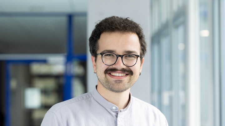 Frieder Rodewald. He is wearing a white shirt and is standing next to a window wall.
