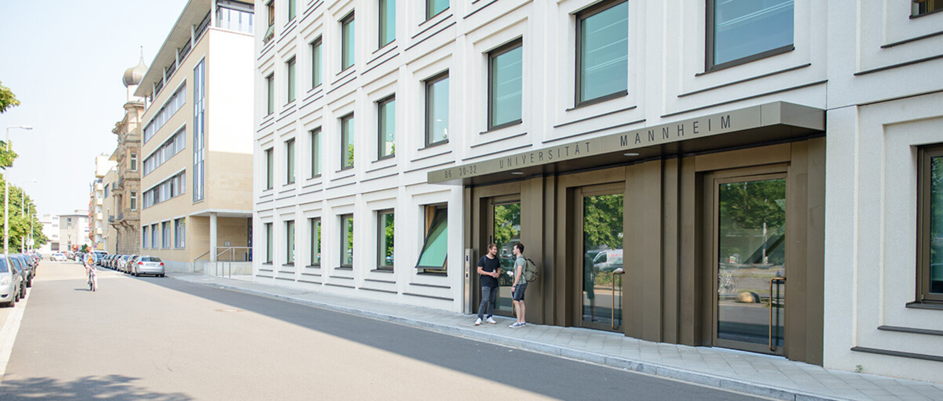 Modernes Universitätsgebäude in B6 in Mannheim mit zwei Studierenden vor dem Eingang.